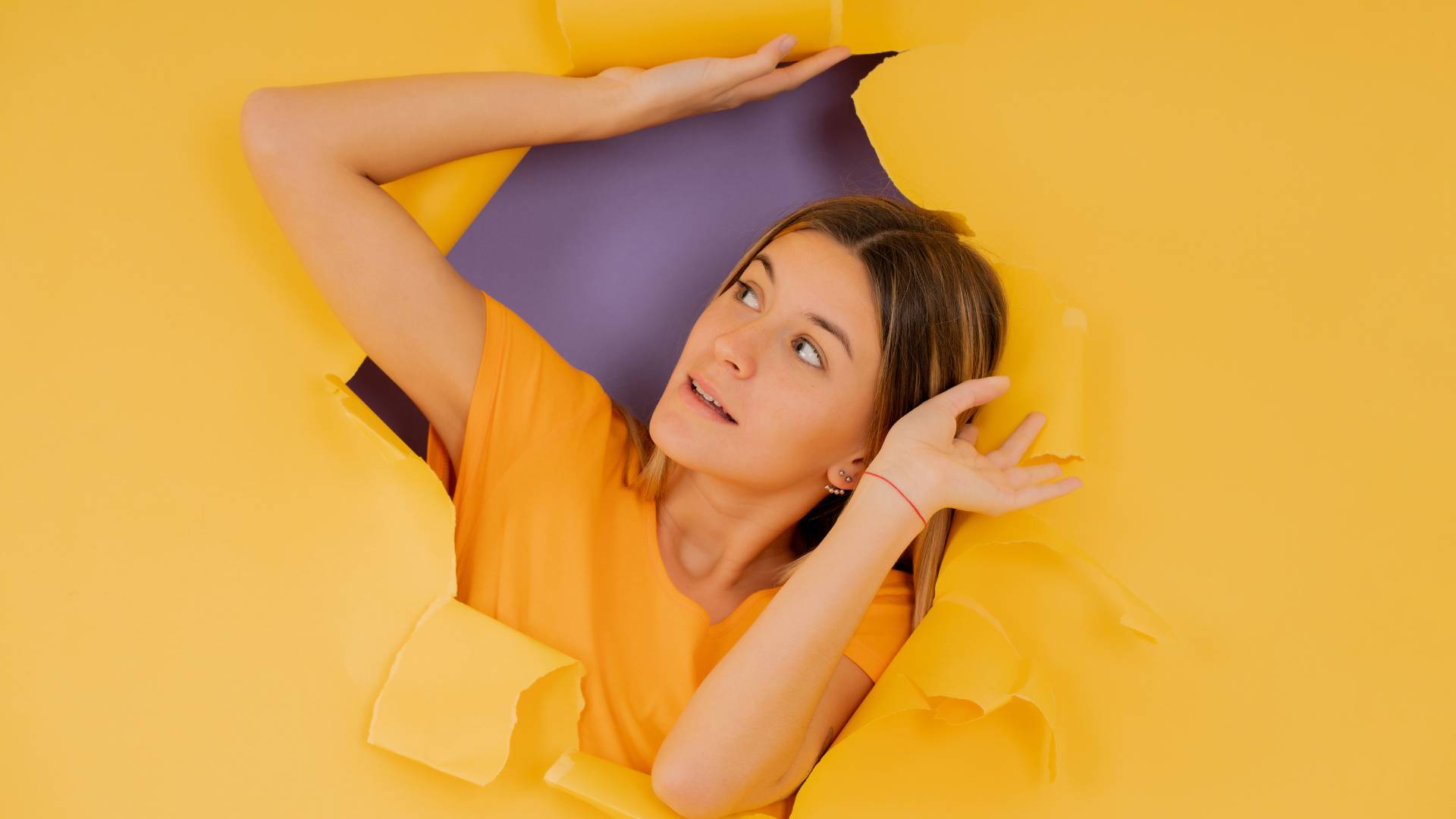 woman looking through a hole in a yellow wall to illustrate how to find mouse entry point